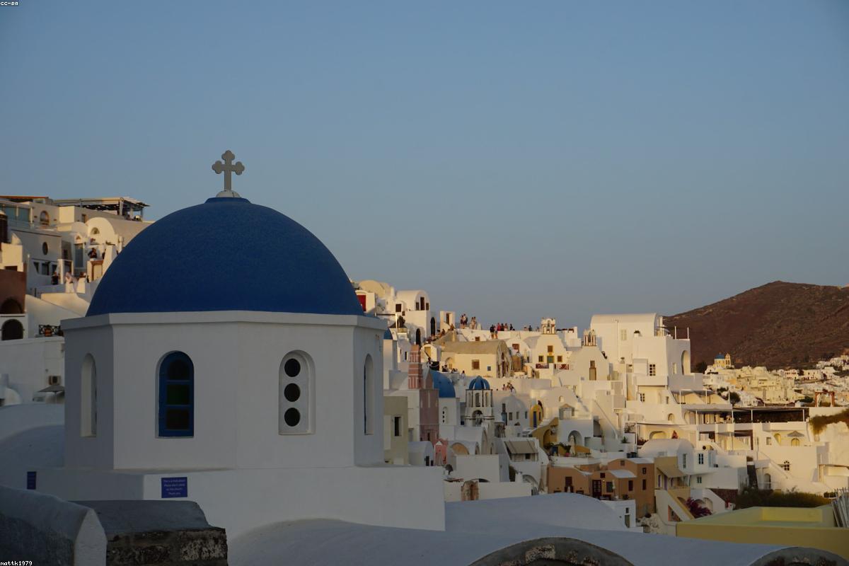 The blue-and-white buildings of the Greek town of Santorinia and the Aegean Sea sunset